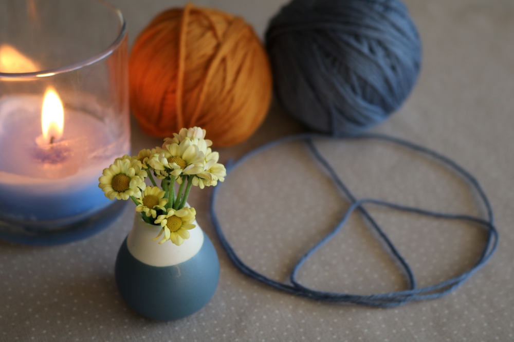 A bunch of little yellow flowers next to a piece sign laid out with a thread of wool